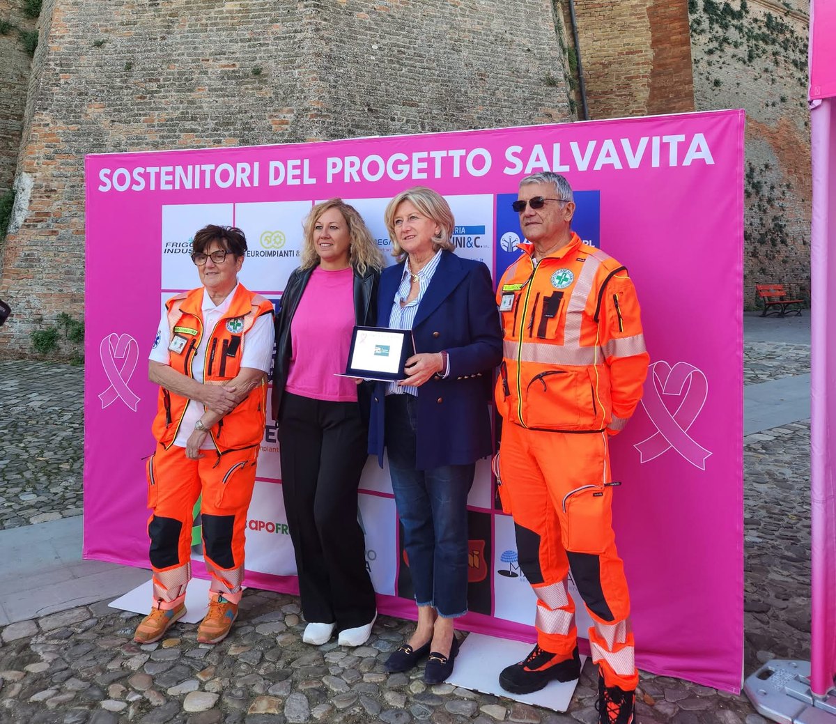 Consegna della targa di encomio a Pulzoni Antonelli davanti al fondale dei sostenitori del Progetto Salvavita, in Piazza del Popolo a Cesena